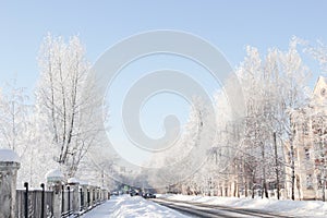 Snowy street in a small town with trees under rime in winter