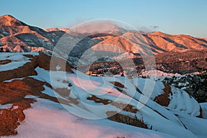 A snowy sunrise in the Garden of the Gods with Pikes Peak mountain in the background.