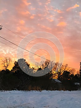 Snowy sunset white frozen cold winter precipitation and beautiful red sunset and sky overhead.