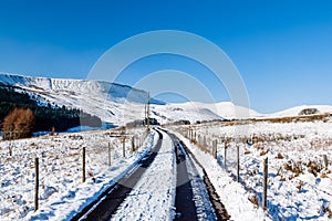 A snowy track leads towards snow capped mountains