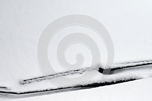 Snowy windshield on a car with wipers. Winter concept for traffic and road safety