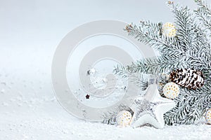 Snowy winter background with christmas tree branch, decorative glass star and balls