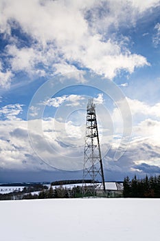 Snowy winter country with transmitters and aerials on telecommunication tower