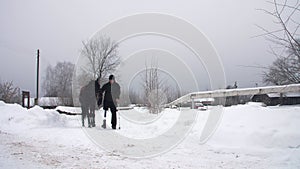 Snowy winter, disabled man jockey leads, holding with reins a black horse on the way. man has a prosthesis instead of