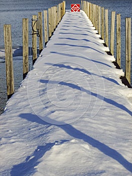 Snowy winter dock with pier shadows