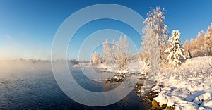 Snowy winter forest with bushes and trees on the banks of the river with fog, Russia, the Urals