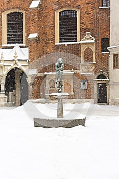 Snowy winter in Krakow, Mariacki Square with a dove well and a bronze statue of a student, Krakow, Poland