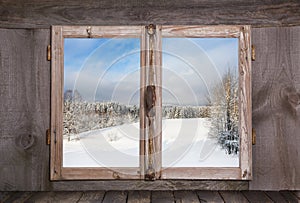 Snowy winter landscape. View out of an old rustic wooden window.