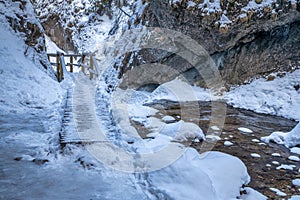 Zasněžená zimní krajina s dřevěným mostem na turistické stezce