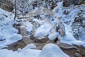 Snowy winter landscape with a wooden bridge on tourist trail thr