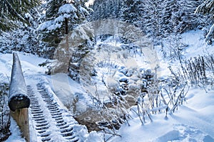 Snowy winter landscape with a wooden bridge on tourist trail thr