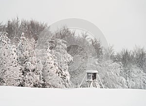 Snowy winter mountain forest scape with a deer stand