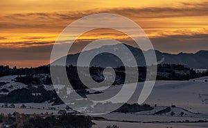 Snowy winter mountain landscape and colorful sky due sunrise over hill Poludnica in Low Tatras mountains at Slovakia