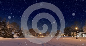 Snowy winter night landscape with glowing street lamps and a distant Christmas tree image