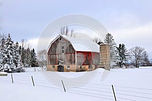 Snowy winter rural landscape with red barn