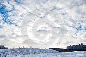Snowy winter scene on cloudy sky. Cumuliform cloudscape over wintry landscape