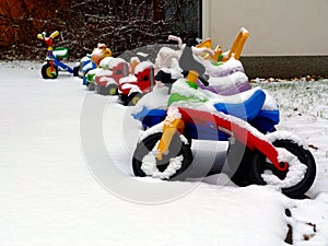 Snowy winter scene of colorful plastic kids toys and scooters in a perspective view