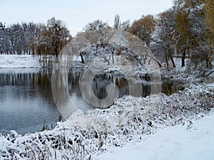 Snowy winter trees along the bank of the river in the thin winter cold fog at the sunset - winter picturesque landscape. Cold