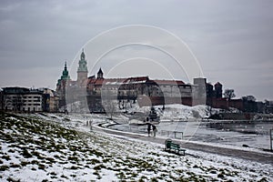 Snowy winter view of Wawel Castle seen from across the Vistula River. Its a cold, cloudy day.Krakow, Poland