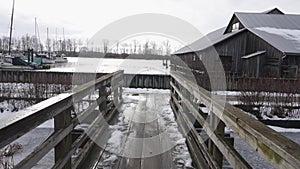 Snowy Wooden Pier Leading to Rustic Boathouse by Frozen River