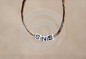`SNS` alphabet white cube in a round rope.