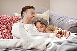 Snuggle time on the sofa always end up being nap time. a man and his son taking a nap on the couch at home.