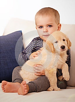 Snuggling his way into his heart. An adorable little boy with his puppy at home.