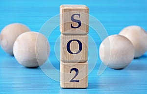 SO2 - acronym on wooden cubes on a blue background with wooden round balls
