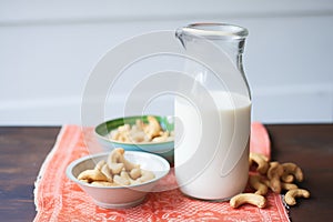 soaked cashews next to a jug of fresh cashew milk