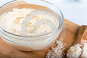 Soaked rice, grain, cloudy liquid water in glass bowl on wooden background