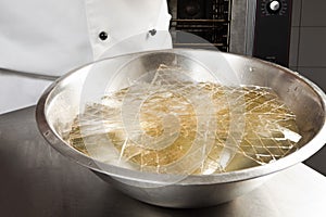 Soaking the gelatine leaves in a bowl of water photo