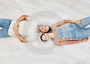 Soaking in the moment. High angle shot of a young couple lying on the floor while moving house.