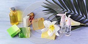 Soap, antiseptic spray and aromatic oil bottles, white lily flower on a wooden table