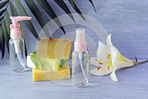 Soap, antiseptic spray and aromatic oil bottles, white lily flower on a wooden table