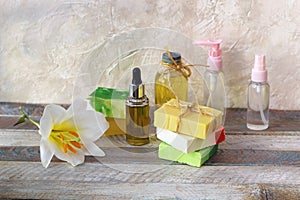 Soap, antiseptic spray and aromatic oil bottles, white lily flower on a wooden table