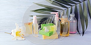 Soap, antiseptic spray and bottles with aromatic oil, white lily flower on a wooden background