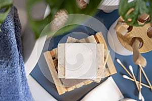 Soap bar with blank label near hygiene products on blue in bathroom top view, mockup