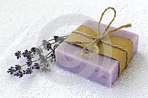 Soap bar with dry aromatic lavender flowers. Purple handmade soap on a white terry cotton towel. Natural toiletries and hygiene