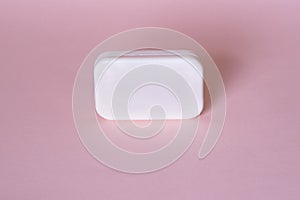 Soap bar in foam with copy space in center isolated on bright pink background.