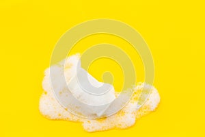 Soap bar with foam on yellow background top-down copy space