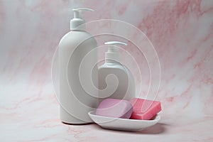 Soap bars and bottle dispensers on pink marble background