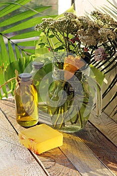Soap, a bouquet of medicinal herbs and bottles with aromatic oil on a wooden table