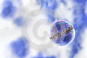 Soap bubble on a background of blue sky, reflection of the city in it