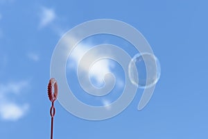 Soap bubble is blown out of the ring against the background of a blue sky with clouds