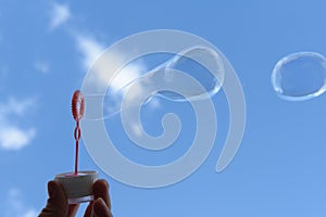 soap bubble is blown out of the ring against the background of a blue sky with clouds