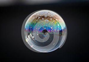 A soap bubble displays swirling patterns