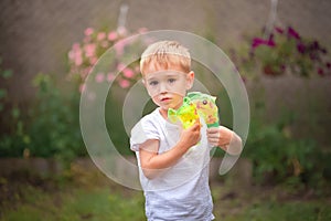 Soap Bubble Games. The boy in the backyard is playing with a water gun. Boy in summer playing with water and soap bubbles close-up