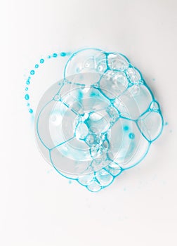 Soap bubbles on a white background from blue shower gel, top view.