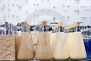 Soap dish dispenser for liquid soap, bathroom ceramic accessories in beige and white colors on glass shelve in store close up