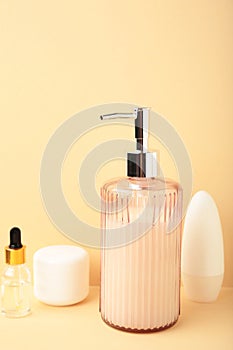 Soap dispenser with bath accessories on beige background